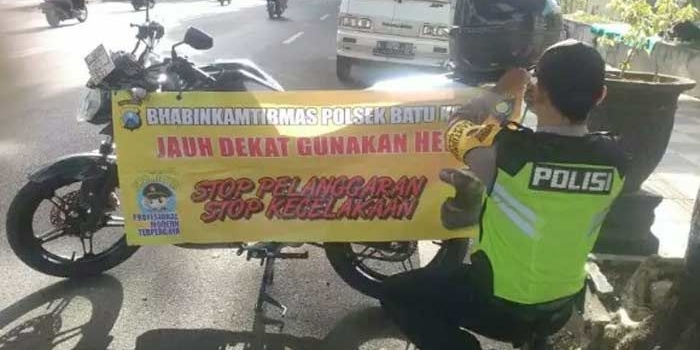 Brigadir Ari Yudiantono, saat memasang imbauan di sepeda motornya.