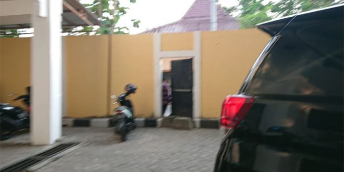 Kepala Dinas Pendidikan (Disdik) Bangkalan Bambang Budi Mustika keluar dari pintu tikus sebelah kiri gedung Kejari untuk mengelabui wartawan yang menunggu. foto: FAUZI/ BANGSAONLINE