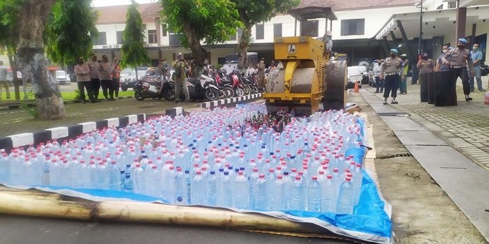 Ribuan botol miras berbagai merek dilindas alat berat.