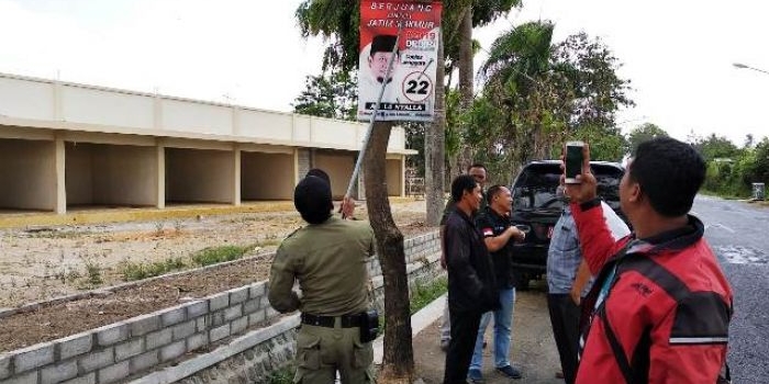 Petugas menertibkan alat peraga kampanye (APK) yang menyalahi aturan. 