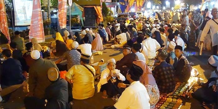 Jemaah yang tidak kebagian tempat di Haul Gus Dur ke-9 terpaksa duduk di jalan raya Jombang-Kediri. foto: RONY S/ BANGSAONLINE