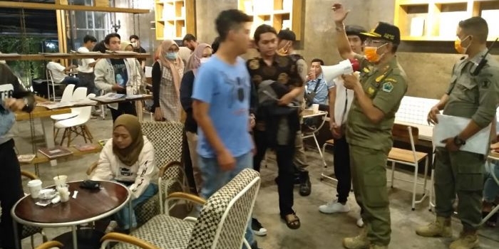 Kasatpol PP Kota Malang Priyadi bersama tim gabungan saat menyosialisasikan SE Wali Kota Malang nomor 6 Tahun 2020. Petugas membubarkan pengunjung Cafe Rocketo, di Jalan Kendalsari Kelurahan Tulusrejo, Lowokwaru Kota Malang untuk antisipasi penyebaran Virus Corona, Sabtu (21/03) malam. foto: IWAN IRAWAN/ HARIAN BANGSA