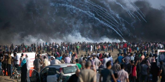 Gas air mata yang ditembakkan oleh pasukan Israel jatuh di atas warga Palestina yang protes di perbatasan Jalur Gaza dengan Israel, Jumat, 13 Juli 2018. Kementerian Kesehatan Gaza mengatakan seorang warga Palestina berusia 15 tahun tewas atas tembakan Israel tersebut. (AP Photo/Khalil Hamra)