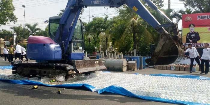 Alat berat backhoe saat memusnahkan ribuan liter miras di halaman Mapolres Tuban.