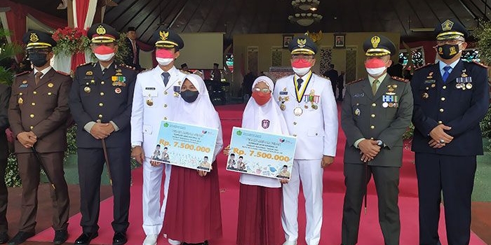 Bupati Pamekasan, Baddrut Tamam, saat memberi penghargaan kepada dua murid SD yang memperoleh perak di tingkat nasional.