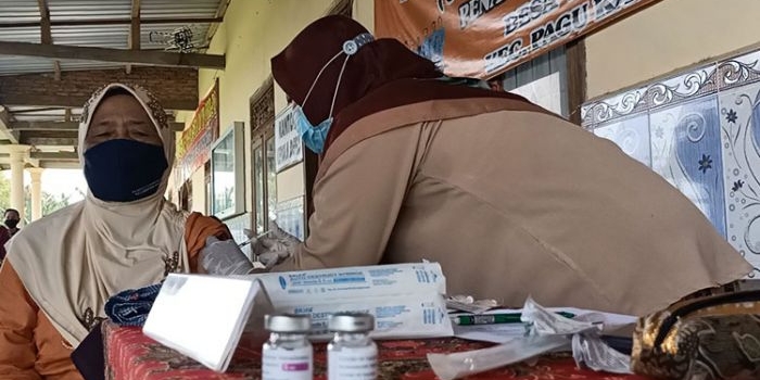 Yeni, Bidan Desa Kambingan, Kecamatan Pagu, Kabupaten Kediri saat menyuntikkan Vaksin AstraZeneca kepada salah satu lansia di Balai Desa Kambingan, Kamis (1/4/2021). (foto: MUJI HARJITA/BANGSAONLINE)