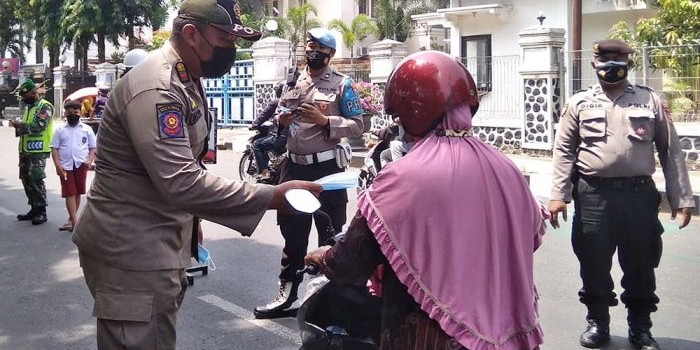 Petugas gabungan saat melakukan operasi nonyustisi, salah satunya dengan membagikan masker kepada pengguna jalan. Foto: Ist