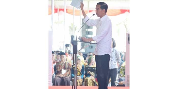 Presiden Jokowi saat memperlihatkan sertifikat tanah di depan masyarakat yang akan menerimanya.