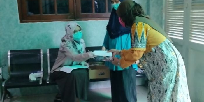 Ning Zahroh, putri Nyai Hj. Alif Fadlilah saat membagikan uang, kurma dan sewek kepada para janda di kediamannya Jalan Siwalankerto Utara, Jumat (22/5/2020). FOTO: MMA/ bangsaonline.com 