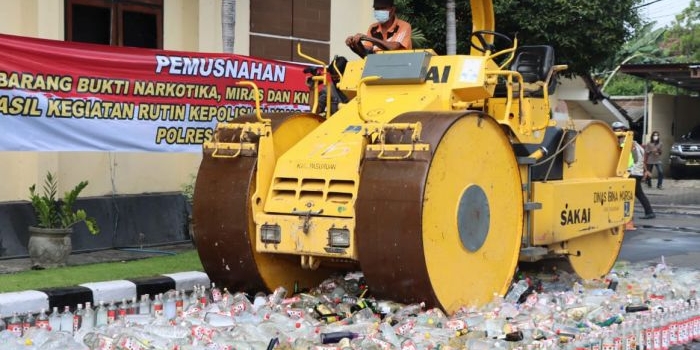Pemusnahan ribuan botol miras menggunakan alat berat jenis roller.