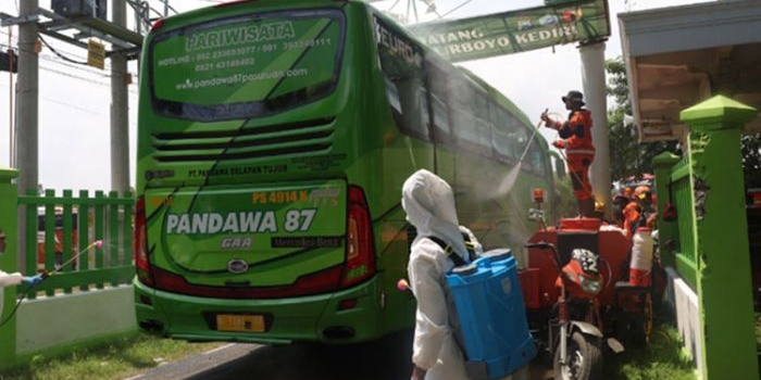 Bus yang akan mengangkut para santri pulang ke daerahnya masing-masing, sedang disemprot dengan cairan disinfektan ketika memasuki pintu gerbang Ponpes Lirboyo. (foto: ist)