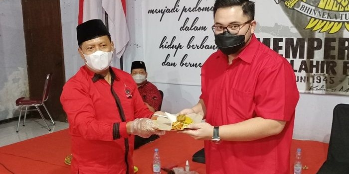 Ketua DPC PDI Perjuangan Kabupaten Kediri, Murdi Hantoro saat menyerahkan potongan tumpeng kepada Bupati Kediri Hanindhito Himawan Pramana disaksikan oleh Ketua DPRD Kabupaten Kediri Dodi Purwanto (duduk). foto: MUJI HARJITA/ BANGSAONLINE