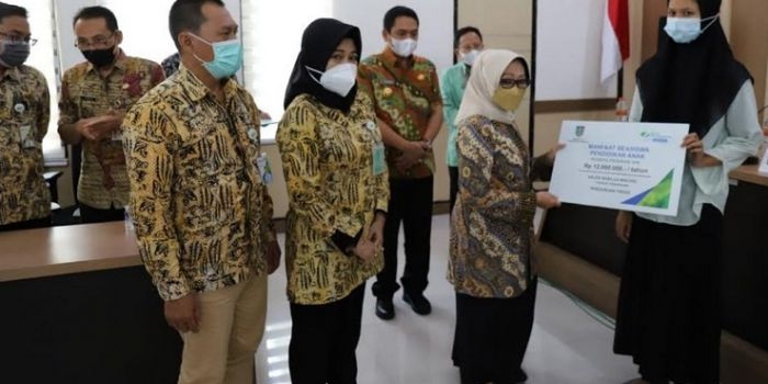 Bupati Jombang, Hj. Mundjidah Wahab menyerahkan beasiswa pendidikan pada ahli waris peserta JKM.
