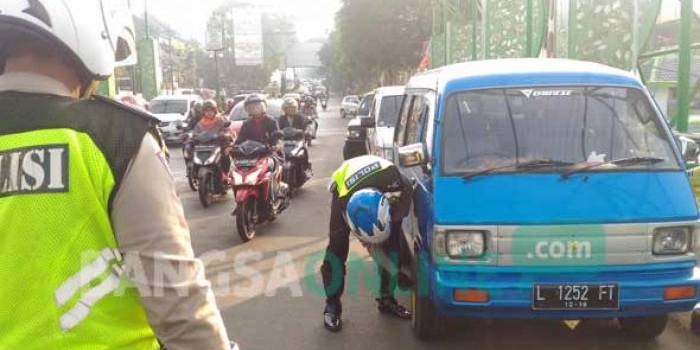 Petugas saat menggembosi salah satu ban mobil yang parkir di atas jembatan kampung putih, Kamis (20/07). foto: IWAN IRAWAN/ BANGSAONLINE