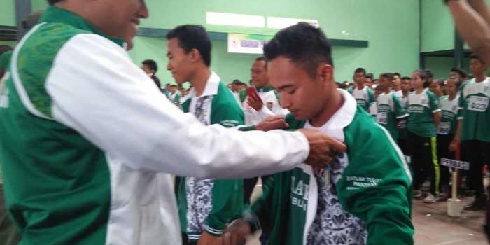 Mirza, Ketua KONI Tuban saat mengenakan jaket kepada atlet.
