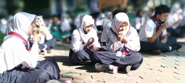 Kegiatan siswa makan telur bersama di halaman SMPN 4 Kota Madiun sebelum masuk kelas.