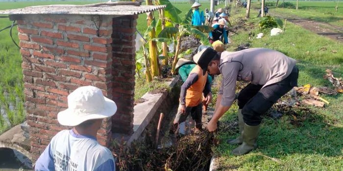 Anggota Polsek Ngawi, bersama warga membersihkan saluran irigasi persawahan di Desa Tempuran, Kecamatan Paron, Ngawi, Minggu (23/10/2022).