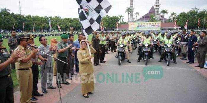Bupati Jombang, Nyono Suharli, dan Wabup Jombang Munjidah Wahab (bawa bendera) saat memberangkatkan rombongan tiga pilar. foto: rony suhartomo/ BANGSAONLINE