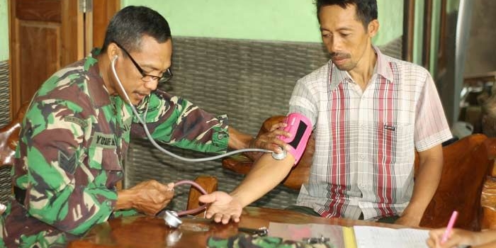 ?Serma Yusuf saat cek kesehatan warga yang datang ke poskes TMMD Kodim 0810 Nganjuk. Foto: BAMBANG/ BANGSAONLINE 
