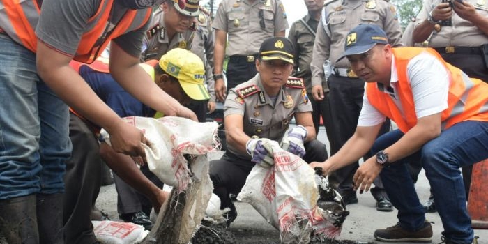 Kapolres Sidoarjo menyempatkan diri ikut memperbaiki jalan berlubang yang mengakibatkan laka dan kemacetan di Jalan Raya Gedangan