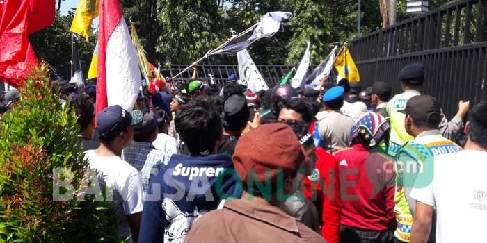 Ratusan pendemo saat mendorong gerbang kantor Pemkab Gresik hingga jebol. foto: SYUHUD/ BANGSAONLINE