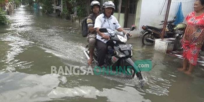 Warga melintasi jalanan yang masih terendam banjir di Desa Rejoagung, Kecamatan Ploso, Kabupaten Jombang, Jumat (13/1). foto: RONY S/ BANGSAONLINE