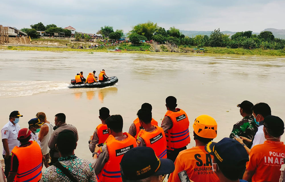 Petugas gabungan saat sedang mencari belasan korban menggunakan perahu karet di aliran Sungai Bengawan Solo yang terpantau banjir dan sedang mengalir deras.