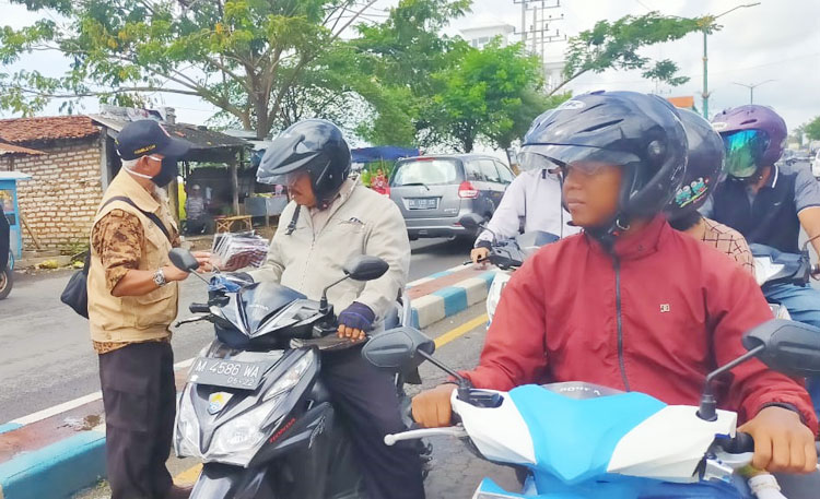 Pengurus Kwarran Gerakan Pramuka Kecamatan Kota Sumenep saat membagikan masker gratis kepada para pengguna jalan raya.