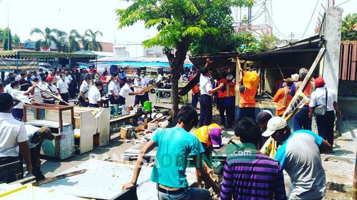 Petugas keamanan dari PT KAI saat membongkar beberapa lapak bangunan. foto: arif kurniawan/ BANGSAONLINE