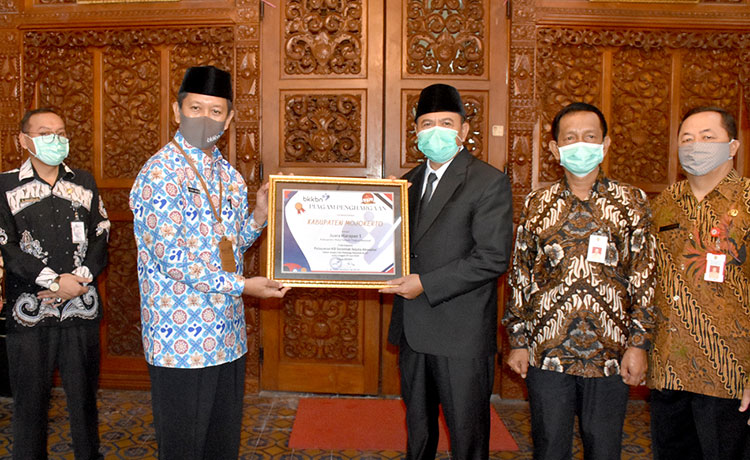 Bupati Pungkasiadi saat menerima penghargaan bidang KB yang diserahkan oleh Kepala Perwakilan BKKBN Provinsi Jawa Timur, Sukaryo Teguh Santosa. (foto: ist).
