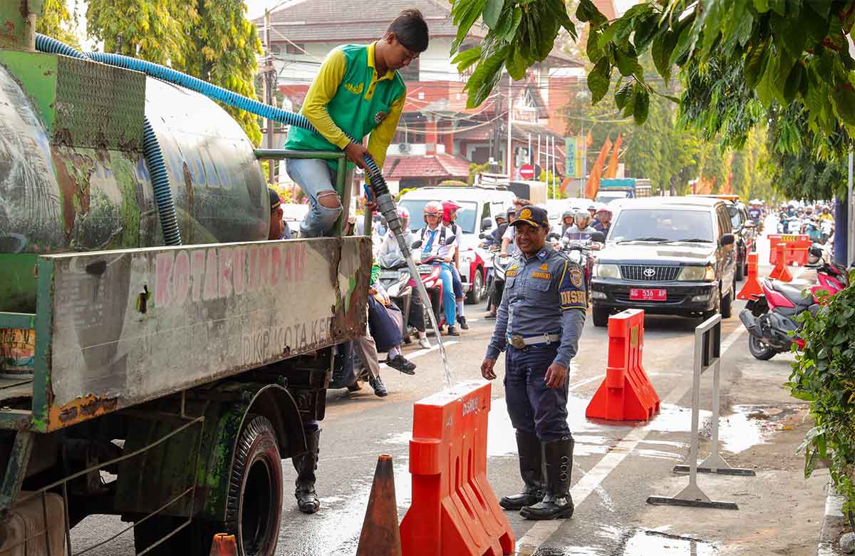 Petugas saat mengisi air untuk pembatas jalan agar tidak digunakan untuk parkir liar. Foto: Ist