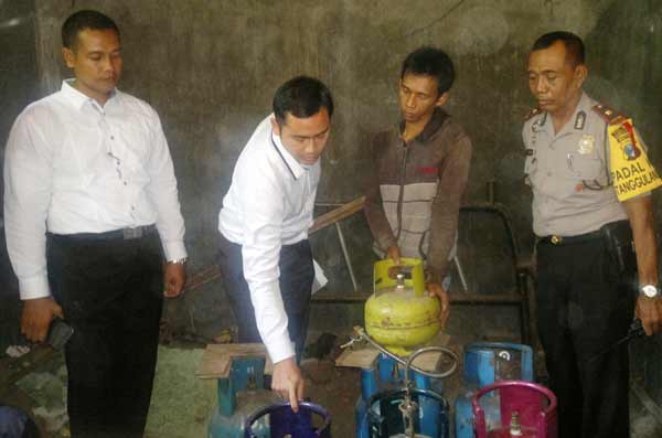 OPLOSAN. Pekerja tempat pengoplosan elpiji, Rudianto (dua dari kanan) sedang mempraktekkan cara memindahkan elpiji dari ukuran bersubsidi ke tabung elpiji non subsidi, kemarin. foto : catur andy/BANGSAONLINE