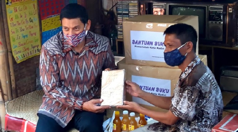 Wali Kota Kediri Abdullah Abu Bakar (kiri) saat menerima pemberian buku jadul dari Budi Santoso di gubuk yang dijadikan semacam perpustakaan. foto: Muji Harjita/ BANGSAONLINE.com