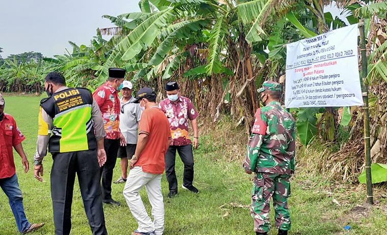 Warga saat memasang spanduk di lahan seluas 3 hektare di Desa Beji, Kecamatan Beji.