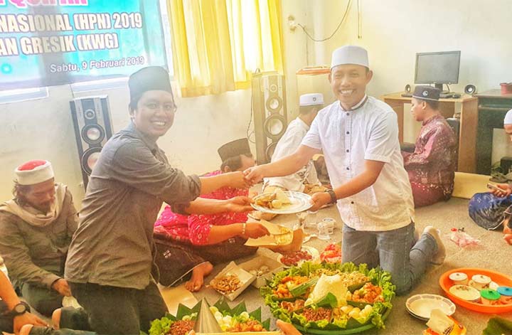 Ketua KWG M. Syuhud Almanfaluty menyerahkan potongan tumpeng kepada Ketua Panitia HPN KWG 2019, Khanif Rosyidi.