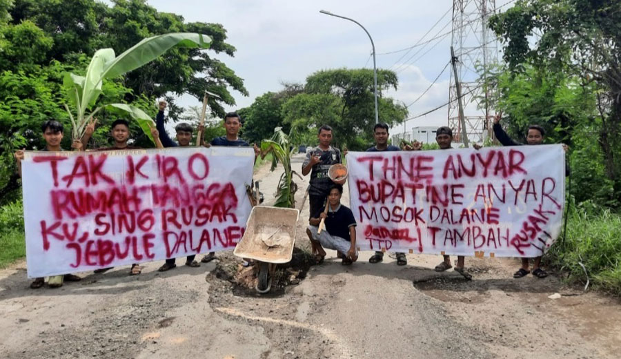 Pemuda Desa Sumberejo, Kecamatan Manyar, Kabupaten Gresik, membentangkan spanduk di tengah jalan dan sebagai bentuk protes atas jalan rusak. Foto: Ist
