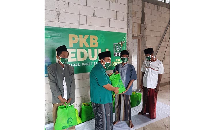 Ketua DPAC Arosbaya, KH. Drs. Moh. Jamhuri saat menyerahkan bantuan  sembako kepada masyarakat terdampak pandemi Covid-19.