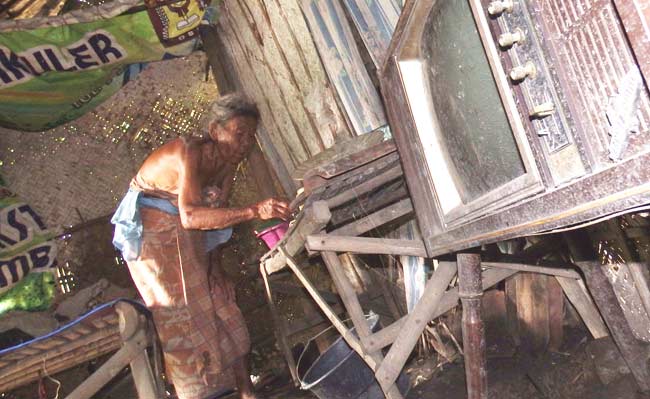 Mbah Paini bersama gubuk reyotnya yang hampir roboh. foto: BANGSAONLINE