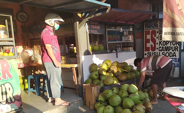 Pedagang kelapa muda sedang melayani pembeli.