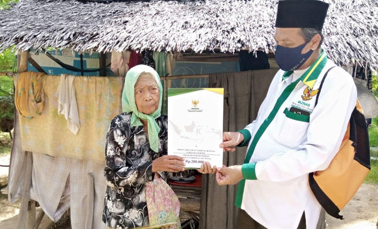 Salah satu relawan Baznas Sumenep saat menyalurkan ZIS kepada warga penerima.