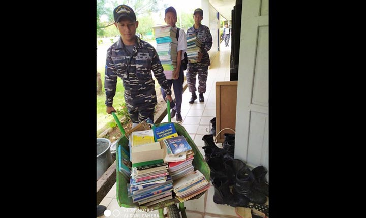 Para Prajurit KRI Yos Sudarso-353 sedang mengangkut ratusan buku ke dalam sekolah.