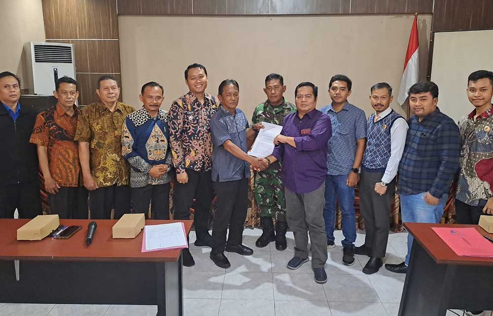 Kusno (depan baju ungu) dan Lurah Gulomantung Jarot Njuwarto disaksikan Camat Kebomas, pejabat forkopimcam, dan tokoh masyarakat menunjukan akta perdamaian. Foto: Ist.