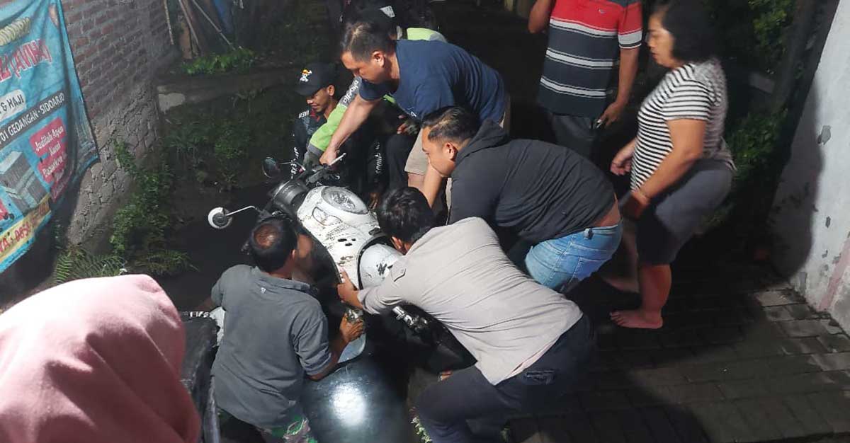 Petugas saat mengevakuasi motor jenis Honda Scoopy dari dalam parit.