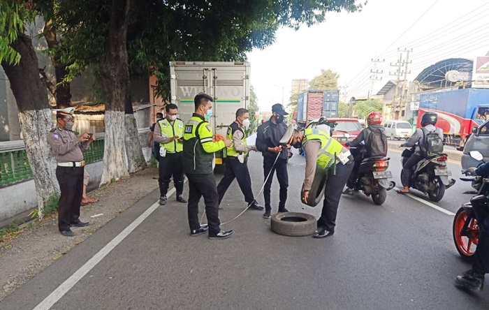 Petugas Satlantas Polresta Sidoarjo sedang mengamankan ban-ban yang dipakai tanda mobil boks sedang mogok.