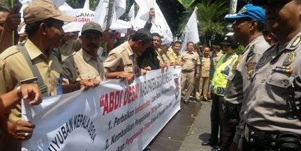 TUNTUT HAK – Kades dan perangkat desa se-Kabupaten Sidoarjo membentangkan spanduk protes di depan Pendopo Delta Wibawa menuntut sejumlah haknya, diantaranya gaji yang belum dibayar selama tiga bulan, Selasa (10/3). foto: musta’in/BangsaOnline.com