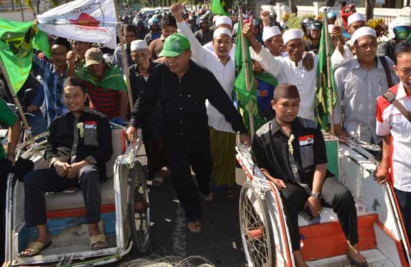 Pasangan calon Ra Hamid-Ra Fadil (naik becak) bersama ratusan pendukungnya saat mendaftar di KPU. (hadi prayitno/BANGSAONLINE)
