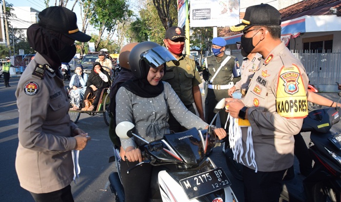Kapolres Pamekasan bersama PJU Polres Pamekasan sedang membagikan masker ke salah satu pengguna jalan raya.