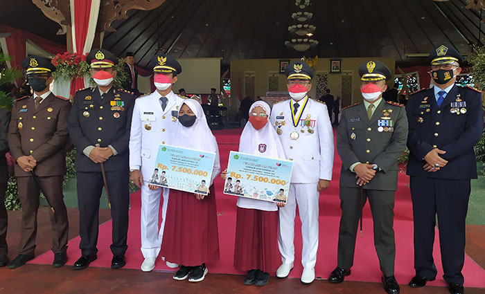Bupati Pamekasan, Baddrut Tamam, saat memberi penghargaan kepada dua murid SD yang memperoleh perak di tingkat nasional.