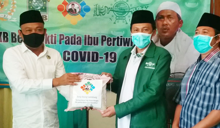Anggota Komisi V DPR RI H. Syafiuddin Asmoro saat menyerahkan paket sembako secara simbolis kepada KH. Makki Nasir, Ketua PCNU Bangkalan.