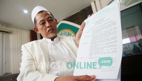 Ketua MUI Jombang menunjukkan fatwa tentang ajaran Gus Jari yang mengaku Nabi Isa. foto: rony suhartomo/ BANGSAONLINE